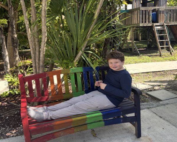 Stefano on a rainbow-painted bench in Little River